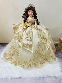 a doll is sitting on top of a white furnishing rug in a gold dress