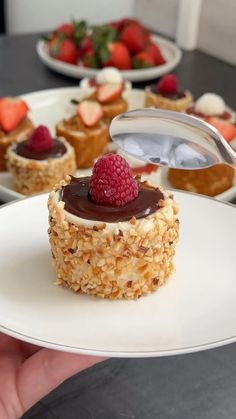 a person holding a plate with desserts on it and strawberries in the background