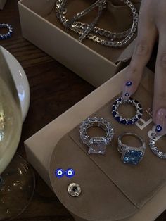 a woman's hand with blue and white nail polish on her nails next to jewelry