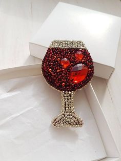 a red glass brooch sitting on top of a white box