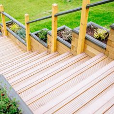 a wooden deck with planters on it and green grass in the backround