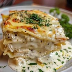 a white plate topped with lasagna covered in cheese and sauce next to broccoli