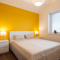 a bedroom with yellow walls and white furniture