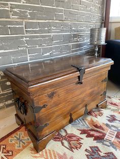 an old trunk sitting on top of a rug in front of a brick wall