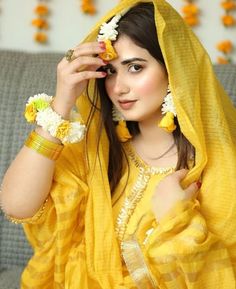 a woman in yellow is holding flowers up to her face and looking at the camera