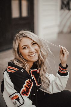 a woman sitting on the ground with her hair blowing in the wind and smiling at the camera