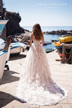 a woman in a wedding dress is standing near boats