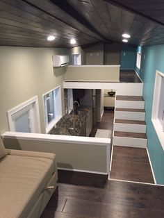 a living room with stairs leading up to the top floor and an open kitchen area