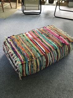 a pile of multicolored rugs sitting on the floor in front of chairs