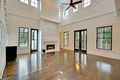 an empty living room with wood floors and large windows on the ceiling, along with two fireplaces