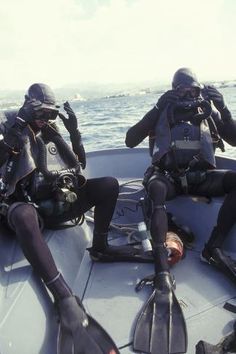 two scuba divers sitting on the back of a boat