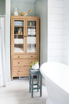 a white bath tub sitting next to a wooden cabinet