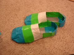 two green and white shoes sitting on the floor next to each other, wrapped in plastic