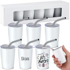 six white tumblers with straws in each one being held by a person's hand