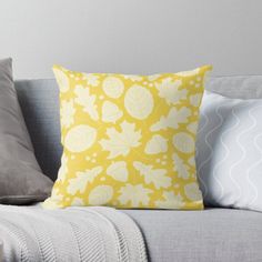 a yellow and white pillow sitting on top of a gray couch next to two pillows