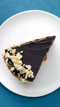 a piece of cake on a white plate with chocolate and coconut flakes around it