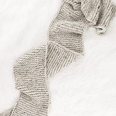 a knitted scarf laying on top of a white blanket