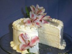 a cake with white frosting and pink flowers on top is cut in half to show the inside