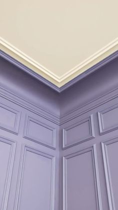 the corner of a room with purple walls and white trim on the ceiling is shown