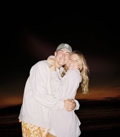 a man and woman hugging on the beach at night