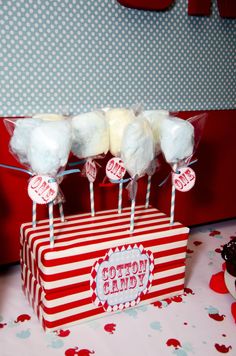 cotton candy lollipops sitting on top of a red and white striped box