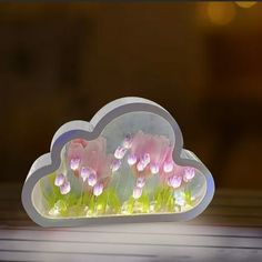 there are pink flowers in the shape of a cloud with green grass growing out of it