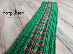 a green knitted table runner sitting on top of a wooden floor