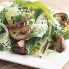 a salad with mushrooms and lettuce on a white plate