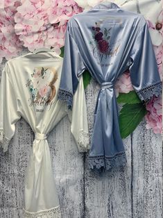 two robes are laying next to each other on a wooden surface with flowers in the background