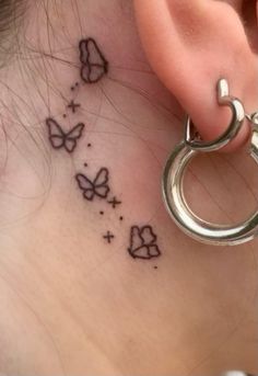 a woman's behind the ear tattoo with butterflies and stars on her left side