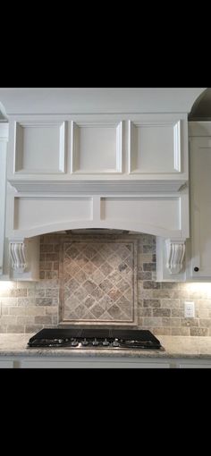 a stove top oven sitting inside of a kitchen next to white cabinets and counter tops