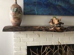 a vase sitting on top of a wooden shelf next to a fire place with branches