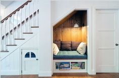 a dog house under the stairs with bookshelves and pillows on it's bed