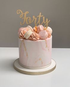 a pink marble cake with gold lettering on top and some macaroni shells in the middle