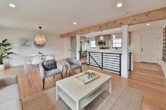 a living room filled with furniture and a white table in front of a staircase leading up to a kitchen