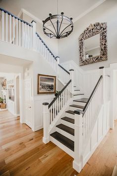 the stairs in this house are white with black trim and wood treads, along with a chandelier