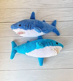 two blue and white stuffed sharks sitting on top of a wooden floor next to each other