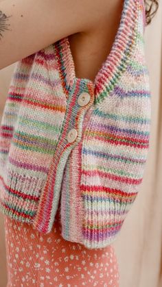 a close up of a woman's arm wearing a multicolored cardigan