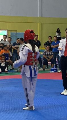 two people standing on top of a blue mat in front of a group of people