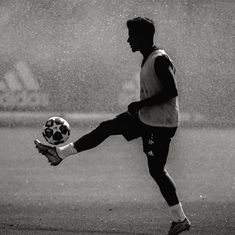 a man kicking a soccer ball in the rain