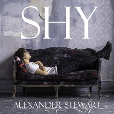 a man laying on top of a couch in front of a wall with the word shy