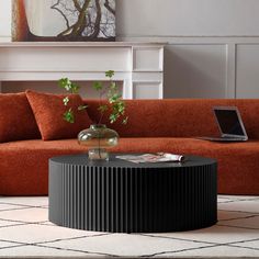 a living room with an orange couch and a laptop on the coffee table in front of it