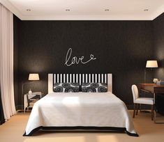 a black and white bedroom with love written on the wall above the bed, along with two lamps