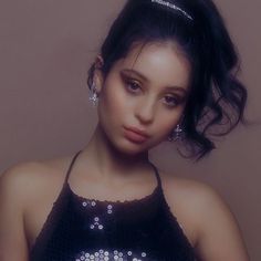 a young woman wearing a black dress with silver sequins on it's chest