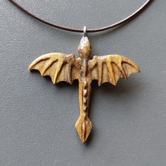 a wooden bat hanging from a leather cord on a gray surface with a necklace attached to it