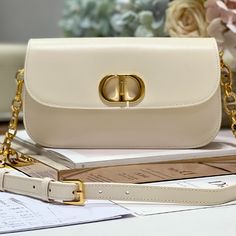 Elevate this classic collection with an elegant design. Crafted in ivory gray smooth calfskin, the rounded flap features a delicate curve and adorned with a metal CD clasp with antiqued gold finish, inspired by the closure of a Christian Dior perfume bottle. Embossed 30 Montaigne signature on the back and a classic chain with alternating gold-finish metal and leather-toned enamel links. Designed with pleats for spaciousness and a refined silhouette, it can be carried by hand, over the shoulder o Elegant Beige Shoulder Bag With Metal Hardware, Elegant Cream Bag With Chain Strap, Elegant Shoulder Bag With Cc Turnlock Closure, Elegant Beige Shoulder Bag With Cc Turnlock Closure, Elegant Shoulder Bag With Metal Hardware, Elegant Rectangular Shoulder Bag With Gold-tone Logo, Formal Cream Shoulder Bag With Chain Strap, Classic White Shoulder Bag With Metal Logo, Classic Gold Shoulder Bag With Metal Logo