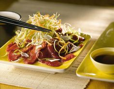 a yellow plate topped with meat and veggies next to a cup of coffee