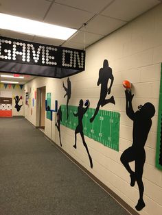 a hallway decorated with silhouettes of football players and the words game on above them