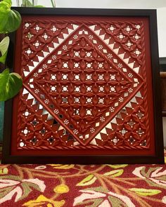 an intricately designed wooden frame sitting on top of a table next to a potted plant