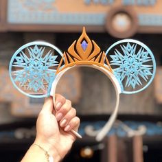 a hand holding up a mouse ears with snowflakes on it